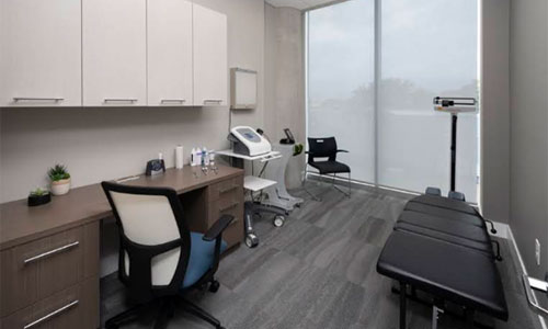 Examination room with treatment table, desk, scale and clinical equipment