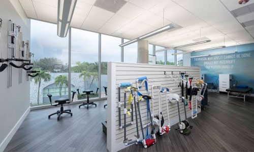 Open rehabilitation gym with therapy tools and floor-to-ceiling windows