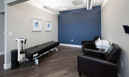 Private treatment room with chiropractic table and patient seating